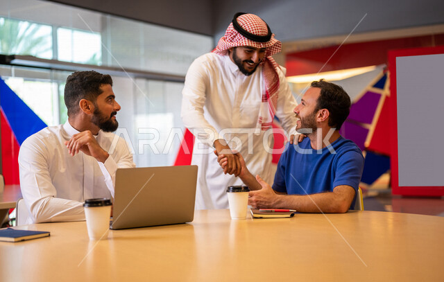 A close-up photo of a group of Arab Saudi Gulf university students in the university cafe, cooperation and sharing, working on the computer, advanced academic universities, Saudi Arab Gulf employees in the company cafe, conversations and discussions, busi