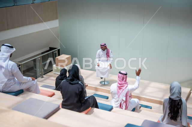 صوره من الخلف لطلاب جامعيون عرب سعوديون خليجيون في قاعة المحاضرات في الجامعه, الإستماع الى المحاضره, ورش عمل, دورات تدريبيه, جامعات أكاديميه متطوره, موظفون عرب سعوديون خليجيون في شركه, إجتماع عمل, الحوارات والنقاشات, فريق عمل سعودي