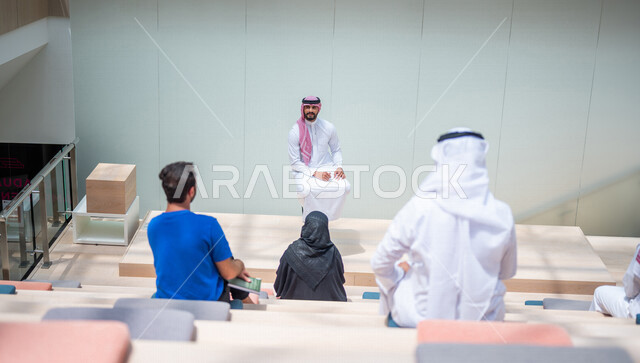 صوره من الخلف لطلاب جامعيون عرب سعوديون خليجيون في قاعة المحاضرات في الجامعه, الإستماع الى المحاضره, ورش عمل, دورات تدريبيه, جامعات أكاديميه متطوره, موظفون عرب سعوديون خليجيون في شركه, إجتماع عمل, الحوارات والنقاشات, فريق عمل سعودي
