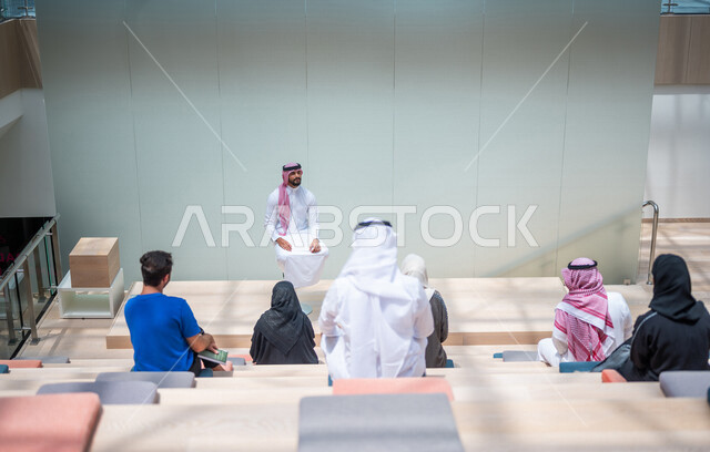 صوره من الخلف لطلاب جامعيون عرب سعوديون خليجيون في قاعة المحاضرات في الجامعه, الإستماع الى المحاضره, ورش عمل, دورات تدريبيه, جامعات أكاديميه متطوره, موظفون عرب سعوديون خليجيون في شركه, إجتماع عمل, الحوارات والنقاشات, فريق عمل سعودي