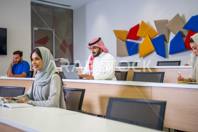 Close-up picture of Arab Saudi Gulf university students in the lecture hall at the university, interaction and participation, taking notes, listening to the lecture, workshops, training courses, lessons and lectures, quality of education, academic univers