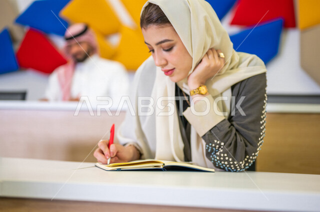 صوره مقربه لطالبه جامعيه عربيه سعوديه خليجيه في قاعة المحاضرات في الجامعه, طلاب جامعيين, تدوين الملاحظات, الإستماع الى المحاضره, ورش عمل, دورات تدريبيه, دروس و محاضرات, جودة التعليم, جامعات أكاديميه في السعوديه, كليات وجامعات متطوره