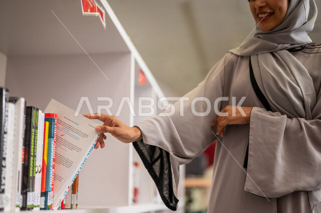 A close-up of a Saudi Arabian Gulf woman in a sophisticated educational university environment, a university student, reading books in the university library, self-education, the concept of reading and culture, quality of education, academic universities 