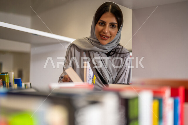 صورة مقربة لإمرأة عربية سعوديه خليجيه في بيئة جامعيه تعليمية متطورة، طالبه جامعيه, قراءة الكتب في مكتبة الجامعه، التعليم الذاتي, مفهوم القراءه والثقافه، جودة التعليم, جامعات اكاديميه في المملكه العربيه السعوديه, برامج أكاديميه, كليات و جامعات متطوره