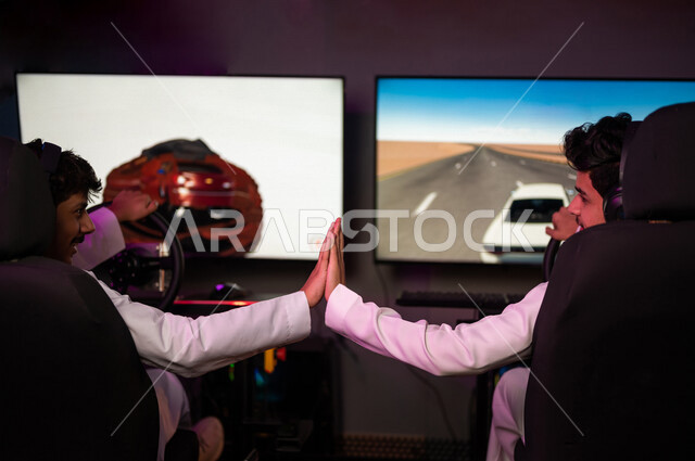 شابان مراهقان عربيان خليجيان سعوديان يتصافحان في متجر الألعاب الإلكترونية، لعبة سيارات سباق، الجلوس خلف عجلة مقود السيارة (يد التحكم)، ألعاب الفيديو الإلكترونية، تكنولوجيا الألعاب، أنشطة ترفيهية، قضاء وقت الفراغ بألعاب الفيديو مع الأصدقاء