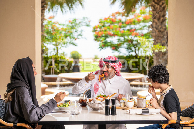 عائلة عربية خليجية سعودية تجلس في المطعم، مائدة طعام مليئة بأصناف متنوعة من المأكولات والمشروبات الشهية، نقاشات وحوارات عائلية، تعابير تدل على السعادة، قضاء أوقات عائلية ممتعة، سفرة طعام، اجواء عائلية سعيدة، مطاعم وكافيهات راقية في السعودية
