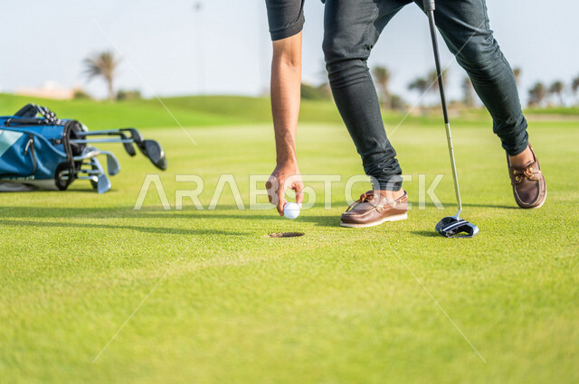 صورة مقربة لرجلان عربيان خليجيان سعوديان، يقوم بإلتقاط كرة الجولف، ممارسة لعبة الغولف على مساحات واسعة خضراء، أنشطة رياضية بالسعودية، لعبة الجولف، رياضات الألعاب الأولمبية الصيفية، أنشطة ترفيهية، الإستمتاع باللعب، ملعب الجولف