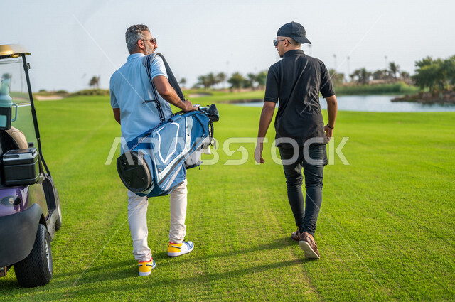 رجلان عربيان خليجيان سعوديان يرتديان الزي الرياضي، ممارسة لعبة الغولف على مساحات واسعة خضراء، أنشطة رياضية بالسعودية، لعبة الجولف، رياضات الألعاب الأولمبية الصيفية، أنشطة ترفيهية، سيارة كهربائية مختصة بنقل الركاب، ملعب الجولف