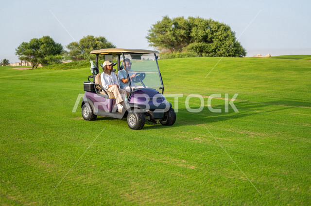 رجل وإمرأة عربيان خليجيان سعوديان داخل سيارة كهربائية مختصة بنقل الركاب، لعبة الغولف ( الجولف ) ، أنشطة رياضية بالسعودية، رياضات الألعاب الأولمبية الصيفية، أنشطة ترفيهية، ملعب الجولف، سيارة كهربائية، نادي الجولف، عربة الجولف