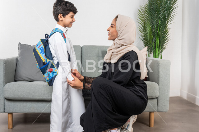 طفل عربي خليجي سعودي يرتدي حقيبة الظهر المدرسية، ارتداء الزي المدرسي، أم تمسك بيد طفلها، الاستعداد للذهاب الى المدرسة، التشجيع والتوجيه، دور الام في توعية الطفل، الدعم النفسي للطفل، الاستعداد للفصل الدراسي الجديد، سنة دراسية جديدة، العودة الى المدرسة