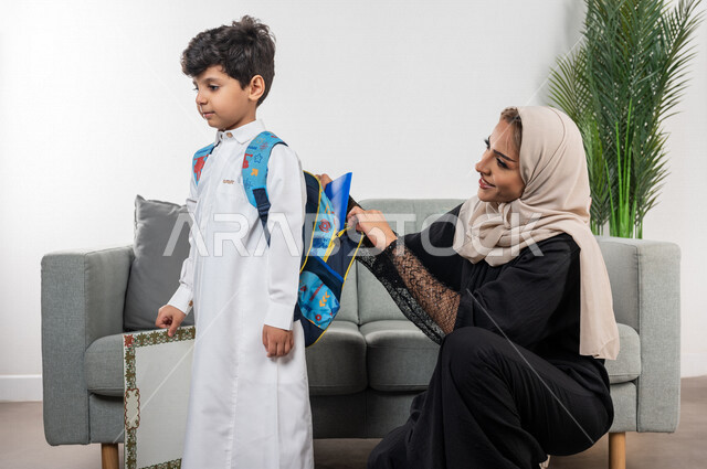 A Saudi Arabian Gulf child wearing a school backpack, wearing a school uniform, preparing and organizing a school bag, getting ready to go to school, getting ready for the new semester, a new school year, back to school, stationery and textbooks