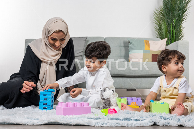 أم عربية خليجية سعودية محجبة تلعب مع طفلها، ممارسة الانشطة الترفيهية، ايماءات وجه سعيدة، مفهوم الأمومة والطفولة، أنشطة ترفيهية للطفل، رعاية الاطفال، تطوير مهارات الطفل، الاهتمام ودعم الأبناء