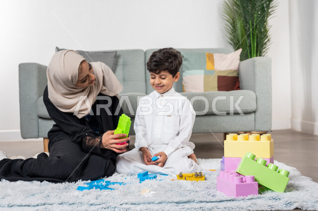 A veiled Saudi Gulf Arab mother plays with her child, practicing recreational activities, facial gestures indicating happiness, the concept of motherhood and childhood, the concept of motherhood and childhood, recreational activities for the child, caring