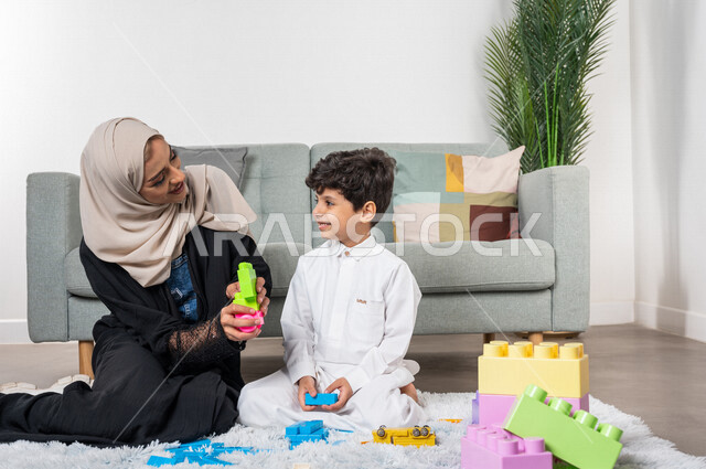 A veiled Saudi Gulf Arab mother plays with her child, practicing recreational activities, facial gestures indicating happiness, the concept of motherhood and childhood, the concept of motherhood and childhood, recreational activities for the child, caring