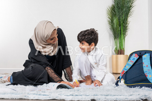 ام عربية خليجية سعودية تساعد طفلها في التعلم  بالمنزل، الانشطة التعليمية، تنمية قدرات الطفل، تشجيع وتطوير الأطفال، مساعدة الطفل بالواجبات المدرسية المنزلية، حقيبة الظهر المدرسية، الاهتمام ودعم الأبناء