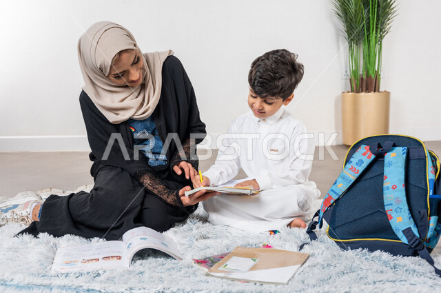 ام عربية خليجية سعودية تساعد طفلها في التعلم  بالمنزل، الانشطة التعليمية، تنمية قدرات الطفل، تشجيع وتطوير الأطفال، مساعدة الطفل بالواجبات المدرسية المنزلية، حقيبة الظهر المدرسية، الاهتمام ودعم الأبناء