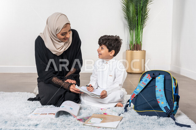 ام عربية خليجية سعودية تساعد طفلها في التعلم  بالمنزل، الانشطة التعليمية، تنمية قدرات الطفل، تشجيع وتطوير الأطفال، مساعدة الطفل بالواجبات المدرسية المنزلية، حقيبة الظهر المدرسية، الاهتمام ودعم الأبناء