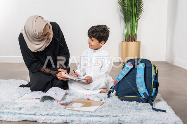 ام عربية خليجية سعودية تساعد طفلها في التعلم  بالمنزل، الانشطة التعليمية، تنمية قدرات الطفل، تشجيع وتطوير الأطفال، مساعدة الطفل بالواجبات المدرسية المنزلية، حقيبة الظهر المدرسية، الاهتمام ودعم الأبناء