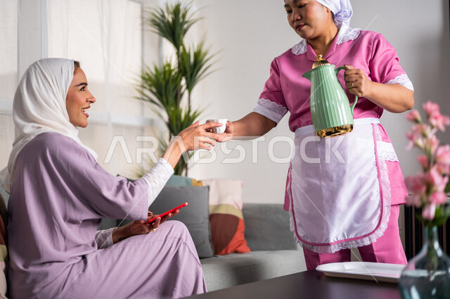 عاملة نظافة ترتدي المئزر ، تقوم بتقديم القهوة لسيدة المنزل ، إستقبال الضيوف ، حسن الضيافة والإستقبال ، المهام والأعمال المنزلية الروتينية ، مدبرة منزل ، خادمة منزلية أجنبية