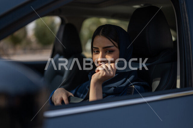صورة مقربة لامرأه عربية خليجية سعودية محجبة تقوم بربط حزام الامان، حرية القيادة للمرأة السعودية، خدمة توصيل الركاب، خدمات النقل الامنة، ايماءات وجه مبتسمة، دروس تعليم قيادة السيارات، قيادة المرأة