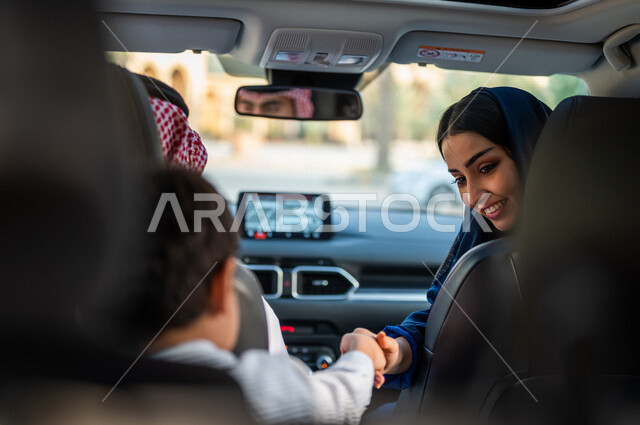 عائلة عربية خليجية سعودية تستمع برحلة في السيارة، انعكاس صورة رجل يقود السيارة على المرآة، امرأة تنظر الى الخلف، خدمة توصيل الركاب، خدمات النقل الامنة، دروس تعليم قيادة السيارات، ايماءات وجه مبتسمة، سيارة الاجرة، قيادة السيارات