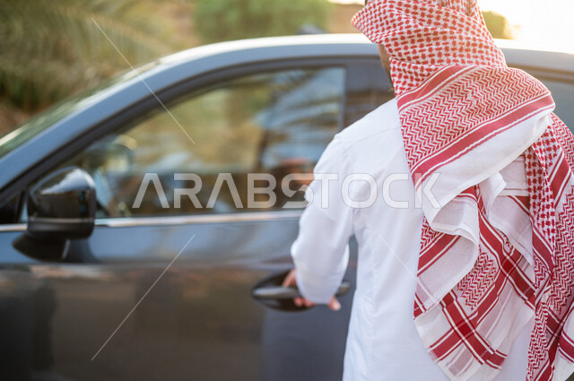 صورة من الخلف رجل عربي خليجي سعودي يفتح باب السيارة، الاستعداد لركوب السيارة، خدمة توصيل الركاب،  خدمات النقل الامنة، دروس تعليم قيادة السيارات، سيارة الاجرة
