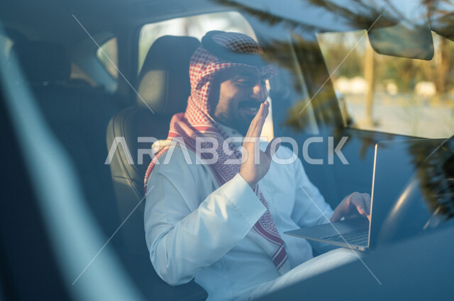 رجل عربي خليجي سعودي يجلس بالسيارة ويستخدم الحاسوب المحمول، مكالمات فيديو اونلاين، تواصل اجتماعي، محادثات ودردشة، بث مباشر، التسويق الإلكتروني، ايماءات وجه مبتسمة وسعيدة، استخدام تقنيات حديثة