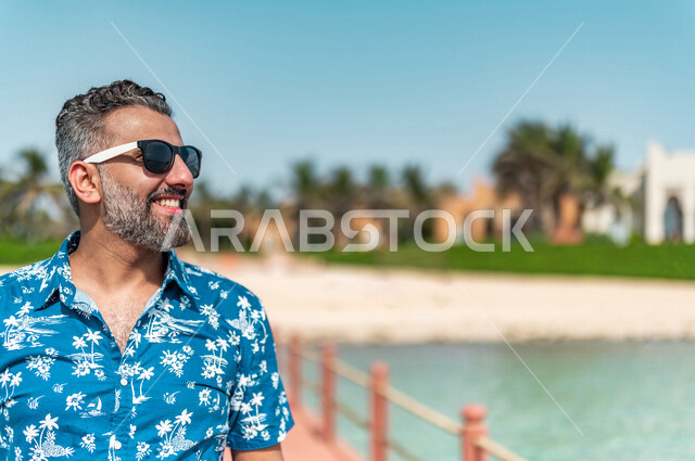 صوره مقربه لرجل عربي سعودي خليجي في رحله صيفيه ممتعه, أنشطه ترفيهيه, جوله على شاطيء بحر جده, الفعاليات الصيفيه, الإسترخاء والإستجمام, الشعور بالسعاده, عطلات سياحيه, منتجع سياحي, ارتداء الملابس الكاجوال الصيفيه, السياحه في السعوديه