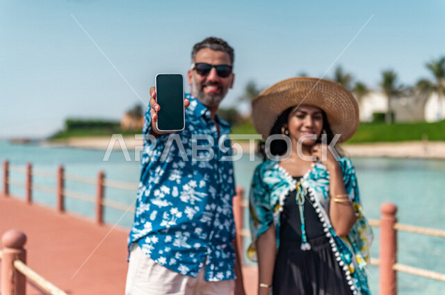 زوجان عربيان سعوديان خليجيان في رحله صيفيه ممتعه, عطله صيفيه, أنشطه ترفيهيه عائليه, جوله على شاطيء بحر جده, عرض شاشه سوداء على الهاتف المحمول, التسويق الإلكتروني, عطلات سياحيه, منتجع سياحي, ارتداء الملابس الصيفيه, السياحه في السعوديه