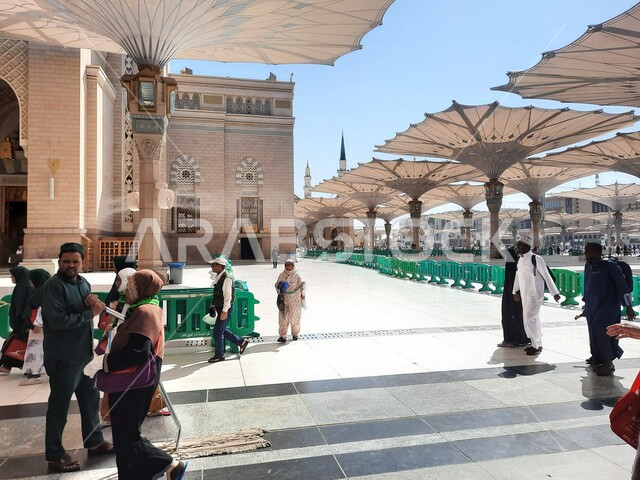 مجموعة من المصلين في ساحة المسجد النبوي الشريف في المدينة المنورة بالمملكة العربية السعودية، العبادة والتقرب الى الله، الحرم النبوي الشريف، أماكن إسلامية مقدسة، المظلات الإلكترونية، إسلاميات وعبادة، معالم دينية إسلامية