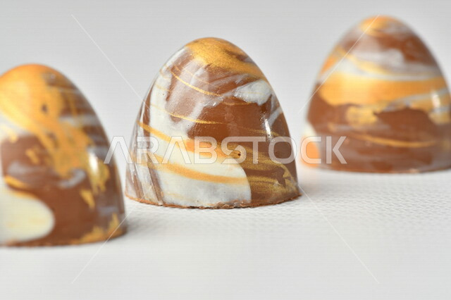 قالب قطع حلوى الشوكولاتة ، صناعة وإعداد حلوى الشوكولاته , مجموعة من حبات الشوكولاتة , حلويات مناسبات واستقبال , حلوى العيد , ترافل بالشوكولاتة , زبدة البندق مع الشوكولاتة، حلويات وسكريات , خلفية بيضاء .