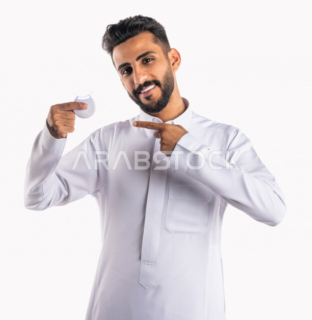 بورتريه بصورة مقربة لرجل عربي خليجي سعودي ، يحمل بيده جهاز تبييض الأسنان المنزلي ، مفهوم العناية والإهتمام بصحة و نظافة الأسنان ، علاجات طب الأسنان ، جلسات العناية بتبييض الأسنان، خلفية بيضاء ، جهاز ليزر