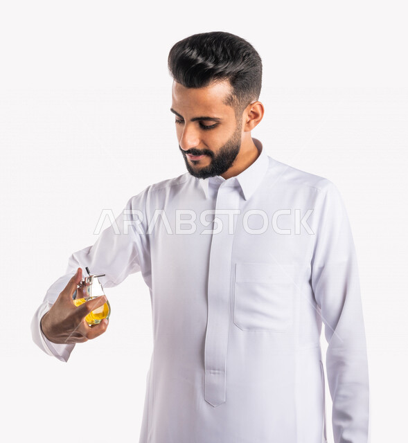 بورتريه بصورة مقربة لرجل عربي خليجي سعودي، يقوم بوضع العطر، التطيب والتعطر، مفهوم الأناقة والإهتمام المظهر الخارجي، عطور ذات روائح فاخرة وفريدة، مناسبات الأعياد وحفلات الزفاف، خلفية بيضاء، التسويق لمنتجات العطور، العود العطري