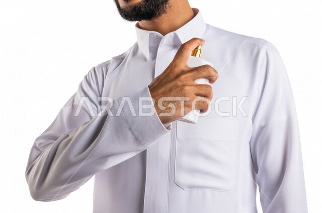 بورتريه بصورة مقربة لرجل عربي خليجي سعودي، يقوم بوضع العطر، التطيب والتعطر، مفهوم الأناقة والإهتمام المظهر الخارجي، عطور ذات روائح فاخرة وفريدة، مناسبات الأعياد وحفلات الزفاف، خلفية بيضاء، التسويق لمنتجات العطور، العود العطري