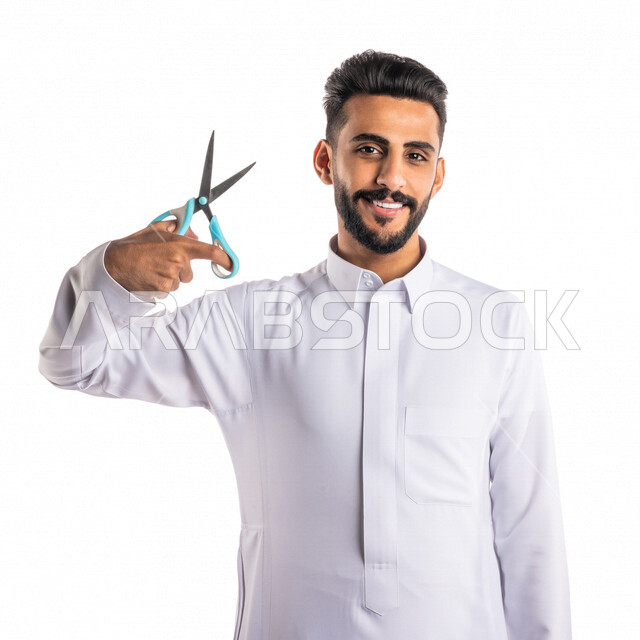 بورتريه لرجل عربي خليجي سعودي ، يحمل بيده المقص ، قص و تصفيف الشعر في صالون الحلاقة ، مفهوم العناية و الإهتمام بالجمال والمظهر الخارجي ، صالون حلاقة تجميلي رجالي ، خلفية بيضاء ، العناية والإهتمام بشعر صحي ونظيف