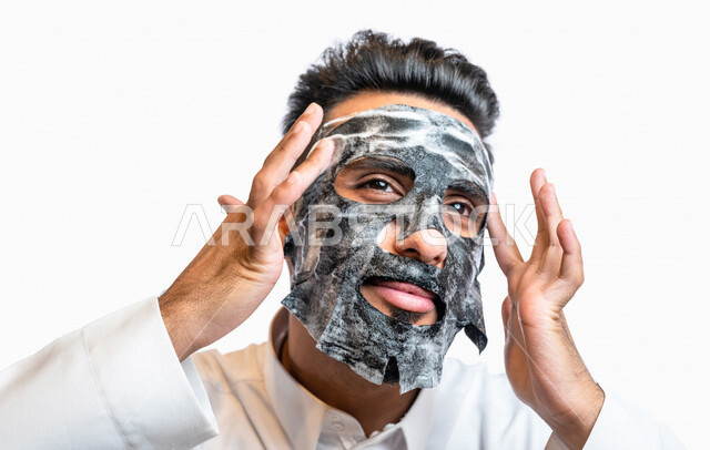 بورتريه لرجل عربي خليجي سعودي، يضع قناع الطين على الوجه، مفهوم العناية والإهتمام بنضارة وتحسين البشرة، روتين العناية بالبشرة، خطوات تنظيف البشرة، تقشير وتفتيح البشرة، إستخدام مكونات تجميلية، جلسات العناية بالبشرة