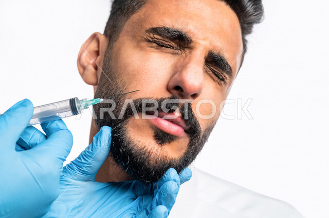 بورتريه بصورة مقربة ليد أخصائي يقوم بحقن مادة البوتوكس على وجه رجل عربي خليجي سعودي، مفهوم العناية والإهتمام بنضارة وتحسين البشرة، جلسات العناية بالبشرة، مكافحة الشيخوخة، عيادة تجميلية رجالية، علاج تجاعيد الوجه، حقن فيلر ( بوتوكس )