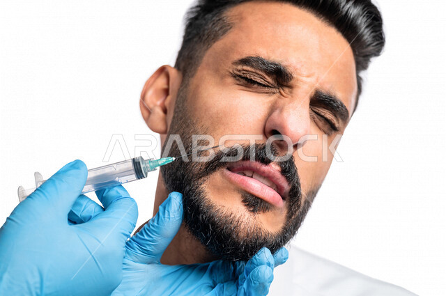 بورتريه بصورة مقربة ليد أخصائي يقوم بحقن مادة البوتوكس على وجه رجل عربي خليجي سعودي، مفهوم العناية والإهتمام بنضارة وتحسين البشرة، جلسات العناية بالبشرة، مكافحة الشيخوخة، عيادة تجميلية رجالية، علاج تجاعيد الوجه، حقن فيلر ( بوتوكس )