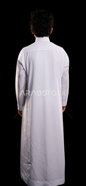 بورتريه من الخلف لولد عربي سعودي خليجي يرتدي الثوب السعودي، يقف بإستقامه، الوقوف بثقه، صوره للجسم بالطول الكامل, خلفية سوداء
