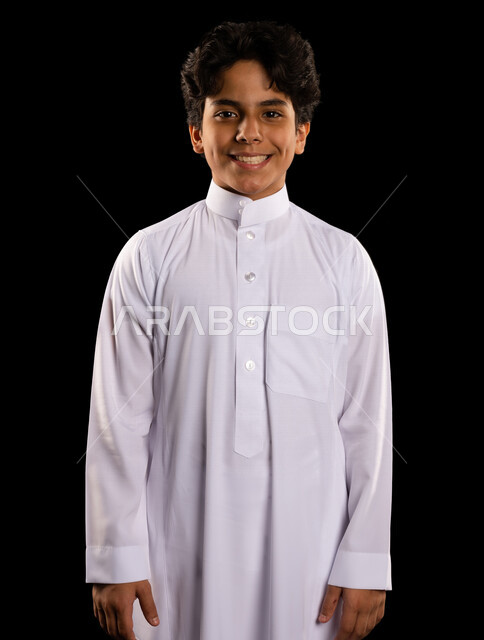 Portrait of a Saudi Arabian Gulf boy wearing the Saudi thobe, standing straight, looking at the camera, confident standing, different face and hands gestures, black background