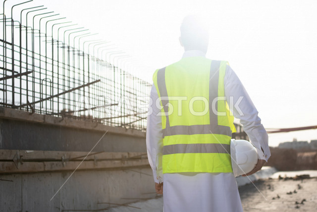 مقاول بناء عربي خليجي سعودي محترف في موقع البناء ، يرتدي سترة و خوذة الحماية ، العمل في موقع البناء ، انجاز الاعمال والمهام