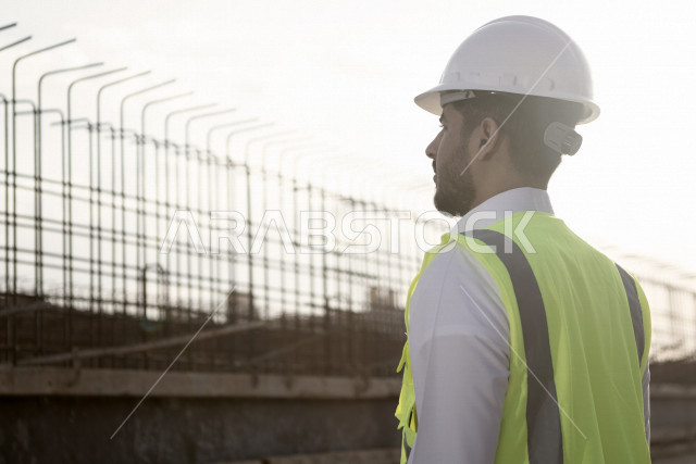 مشرف عمل عربي سعودي خليجي يقف داخل موقع البناء ، يفحص جودة العمل ، يفكر بخطط تطويريه مستقبلية ، بناء خطط استراتيجية ، تحقيق الاهداف ، رؤية مستقبلية