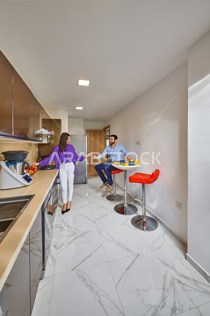 زوجان عربيان يتشاركان في اعداد وجبه الطعام بالمطبخ، الفطور الصباحي, التعاون والمشاركه, مطبخ حديث, مفهوم العائله والأسره