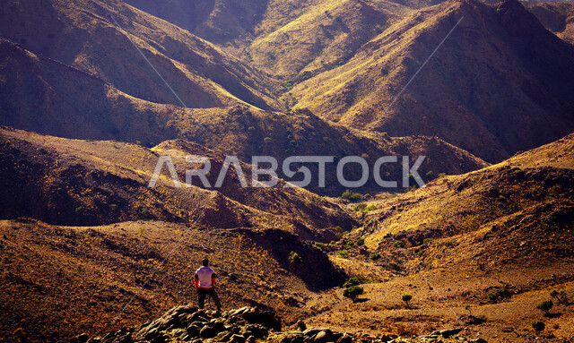 Back view of a tourist holding a camera, mountains and sandy heights in Saudi Arabia, landscapes, mountainous nature in Saudi Arabia, nature background