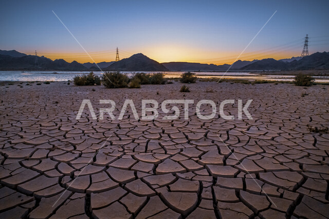 منظر غروب الشمس في صحراء المملكة العربية السعودية ، التشققات الارضية في الصحراء ، جفاف التربة في المنطقة الصحراوية ،  أرض صحراوية جافة ، أرض جافة متشققة