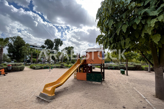  ارجوحة الانزلاق البلاستيكية في احد الحدائق العامة، الاشجار والنباتات الخضراء، ارجوحة اطفال، حدائق ومنتزهات عامة، منطقة مخصصة لالعاب الاطفال