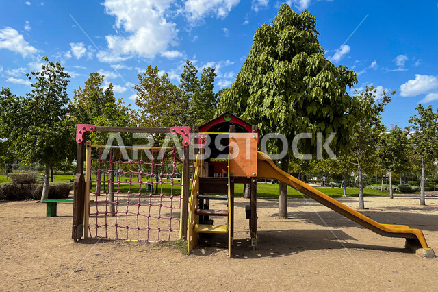  ارجوحة الانزلاق البلاستيكية في احد الحدائق العامة، الاشجار والنباتات الخضراء، ارجوحة اطفال، حدائق ومنتزهات عامة، منطقة مخصصة لالعاب الاطفال
