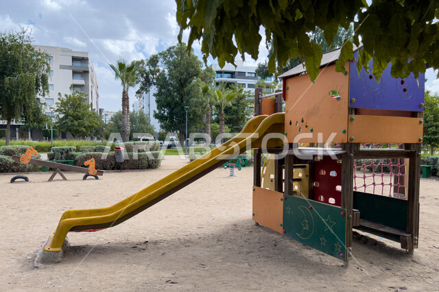  ارجوحة الانزلاق البلاستيكية في احد الحدائق العامة، الاشجار والنباتات الخضراء، ارجوحة اطفال، حدائق ومنتزهات عامة، منطقة مخصصة لالعاب الاطفال