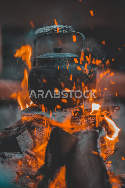 صورة مقربة لابريق الشاي على النيران المشتعلة بالحطب، إعداد وتحضير الشاي، اللهب الأحمر المشتعل، رحلة تخييم، 