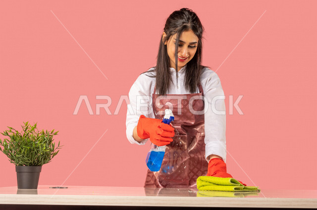 Portrait of an Arab woman wearing gloves and an apron, carrying in her ...